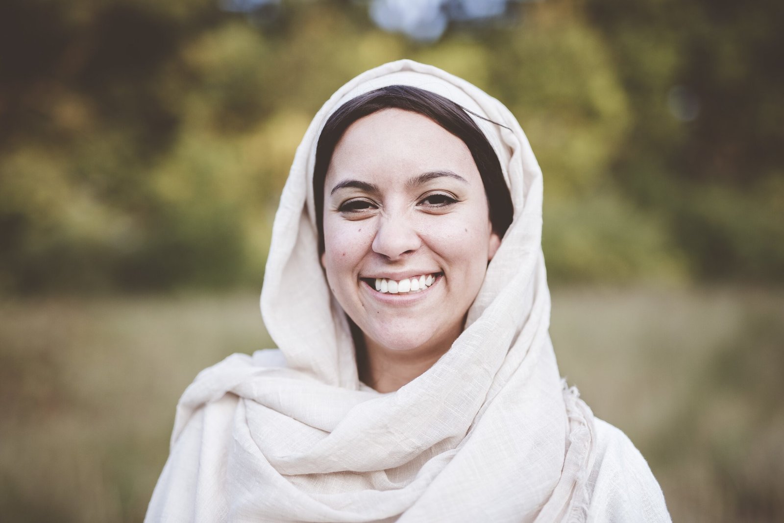 shallow focus shot of a female wearing a biblical robe and smiling towards the camera